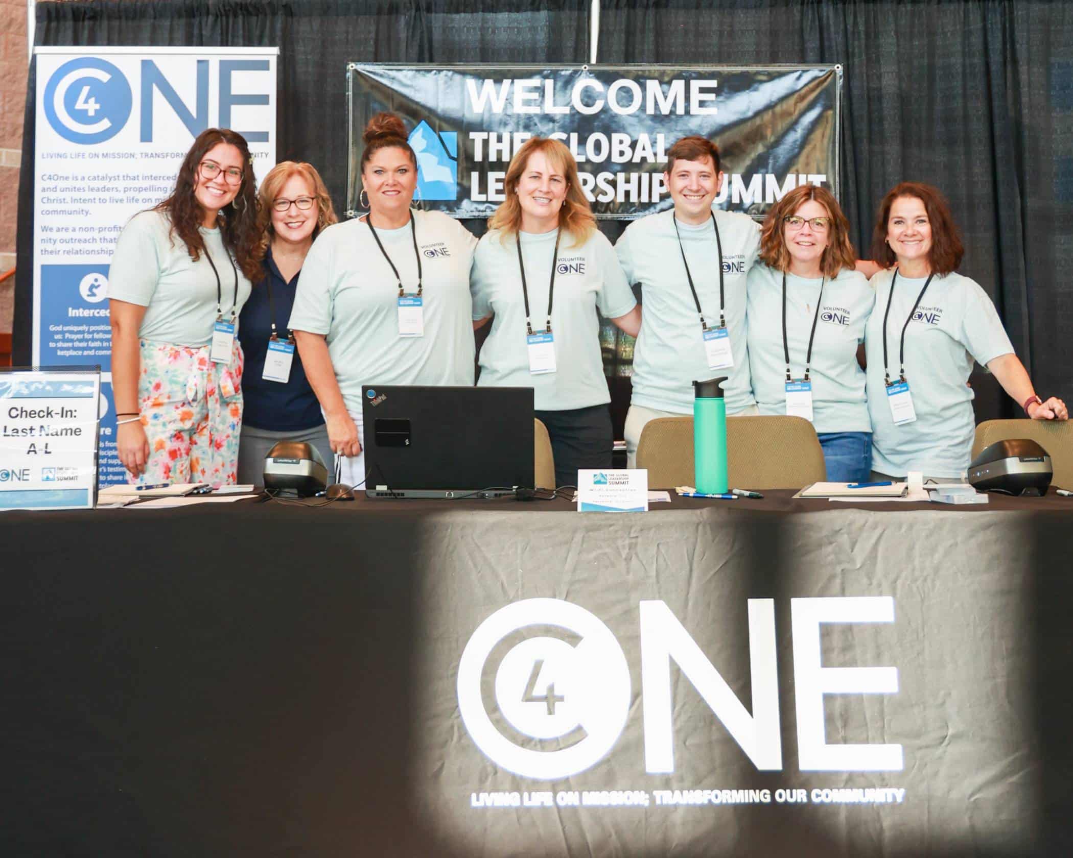C4One staff standing behind the vendor table at the Global Leadership Summit 2023